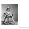1960s little girl putting on shoes sitting on chair by Anonymous