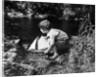 1920s boy putting toy sailboat into stream by Anonymous