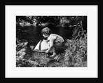 1920s boy putting toy sailboat into stream by Anonymous