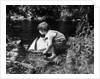 1920s boy putting toy sailboat into stream by Anonymous