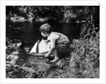 1920s boy putting toy sailboat into stream by Anonymous