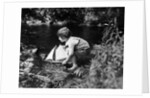 1920s boy putting toy sailboat into stream by Anonymous