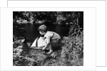 1920s boy putting toy sailboat into stream by Anonymous