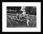 1950s mom & kids serving dad in hammock by Anonymous