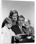 1960s family father mother sons reading book together by Anonymous