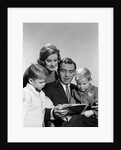 1960s family father mother sons reading book together by Anonymous