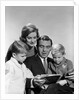 1960s family father mother sons reading book together by Anonymous