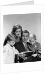 1960s family father mother sons reading book together by Anonymous
