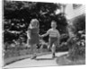 1950s two children holding hands smiling walking along sidewalk by Anonymous