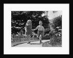 1950s two children holding hands smiling walking along sidewalk by Anonymous