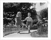1950s two children holding hands smiling walking along sidewalk by Anonymous
