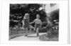 1950s two children holding hands smiling walking along sidewalk by Anonymous