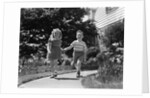 1950s two children holding hands smiling walking along sidewalk by Anonymous