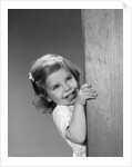 1960s child little girl smiling peeking around corner by Anonymous