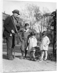 1920s group of three children watching organ grinder's monkey in costume standing on hind legs by Corbis