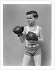 1940s boy child wearing boxing gloves standing ready to fight by Anonymous