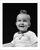 1940s smiling blond boy with big curl on top of head looking up by Anonymous