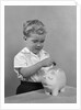 1950slittle boy putting coin into piggy bank by Anonymous