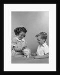 1950s little girl and boy putting coin into piggy bank by Anonymous