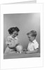 1950s little girl and boy putting coin into piggy bank by Anonymous