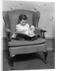 1930s little girl child in large chair with bear reading book by Anonymous