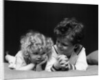 1930s two children brother and sister lying on couch by Anonymous