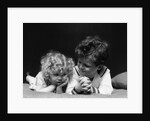 1930s two children brother and sister lying on couch by Anonymous