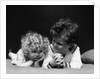 1930s two children brother and sister lying on couch by Anonymous