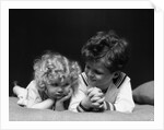 1930s two children brother and sister lying on couch by Anonymous