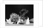 1930s two children brother and sister lying on couch by Anonymous