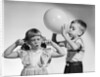 1950s little boy blowing up big balloon little girl with fingers in ears eyes closed by Anonymous