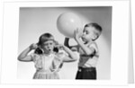 1950s little boy blowing up big balloon little girl with fingers in ears eyes closed by Anonymous