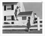 1950s boy walking balancing on fence other children standing sitting next to fence by Anonymous