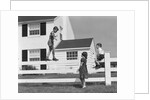1950s boy walking balancing on fence other children standing sitting next to fence by Anonymous