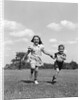 1940s two smiling children running holding hands in grassy field by Anonymous