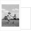 1940s two smiling children running holding hands in grassy field by Anonymous