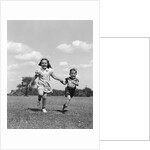 1940s two smiling children running holding hands in grassy field by Anonymous