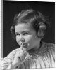 1930s little girl with finger to lips making quiet gesture looking at camera by Anonymous