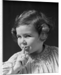 1930s little girl with finger to lips making quiet gesture looking at camera by Anonymous