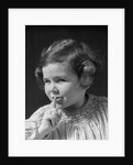 1930s little girl with finger to lips making quiet gesture looking at camera by Anonymous