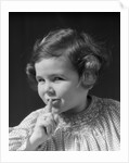 1930s little girl with finger to lips making quiet gesture looking at camera by Anonymous