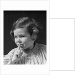 1930s little girl with finger to lips making quiet gesture looking at camera by Anonymous