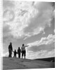 1950s 1960s family of four silhouetted on top rocky hill pointing at clouds in sky by Anonymous