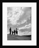 1950s 1960s family of four silhouetted on top rocky hill pointing at clouds in sky by Anonymous
