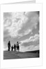 1950s 1960s family of four silhouetted on top rocky hill pointing at clouds in sky by Anonymous
