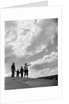 1950s 1960s family of four silhouetted on top rocky hill pointing at clouds in sky by Anonymous