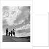 1950s 1960s family of four silhouetted on top rocky hill pointing at clouds in sky by Anonymous