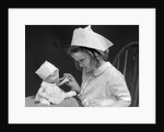 1930s little girl playing nurse with doll spoonful of medicine by Anonymous