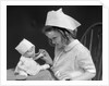 1930s little girl playing nurse with doll spoonful of medicine by Anonymous
