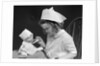 1930s little girl playing nurse with doll spoonful of medicine by Anonymous
